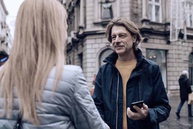 Nachgestellte Szene: Mann mittleren Alters auf der Straße, redend, blonde Frau mit langen Blonden Haaren ihm gegenüber