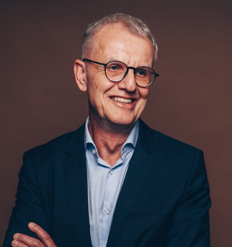 Porträtbild, ca. 60jähriger Mann mit Brille in blauem Anzug